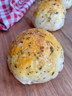 three rolls with cheese and herbs sitting on a cutting board