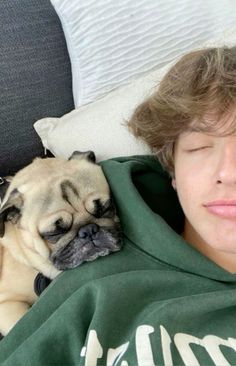 a young boy laying in bed with his pug sleeping next to him on the pillow