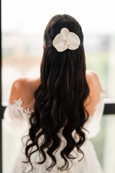 the back of a woman's head with long hair and a flower in her hair