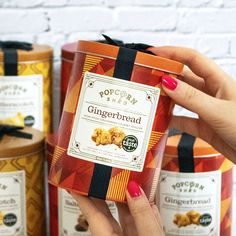 a woman holding up a box of gingerbread cookies in front of some other boxes