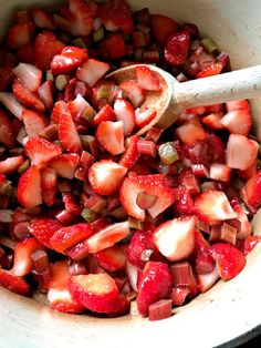 strawberries and onions are mixed together in a bowl with a wooden spoon to stir them