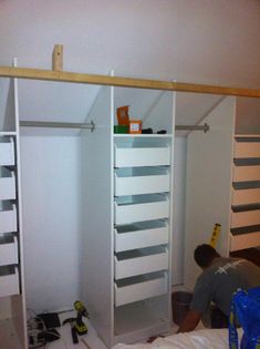 a man is working on some shelves in a closet