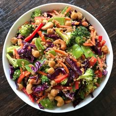 a salad with broccoli, carrots and cashews in a white bowl