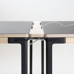 two tables with black metal legs and one has a wooden table top that is attached to it