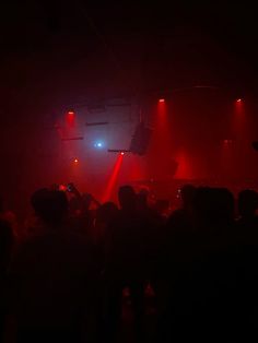 a group of people standing on top of a stage with red and blue lights in the dark