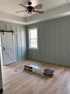 an empty room with hard wood flooring and ceiling fan in the corner, painted gray