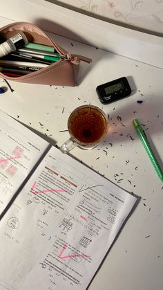 a cup of coffee and some pens on a table next to a calculator