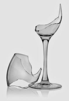 a broken wine glass sitting on top of a table next to an ice cubet