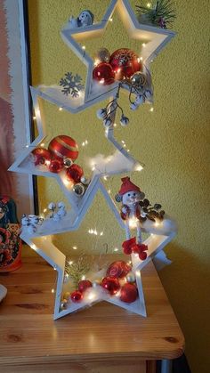 a christmas tree made out of ornaments on a wooden table with a yellow wall in the background