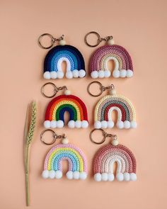 six crocheted rainbow keychains with pom - poms on them