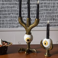 three candles are sitting on a table next to bowls with food in them and one has eyes painted on it