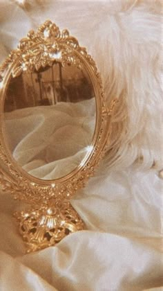 a gold mirror sitting on top of a white bed next to a furnishing