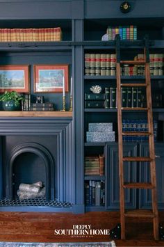 a living room with bookshelves, fireplace and ladder