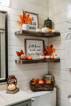 the bathroom is decorated for fall with pumpkins, leaves and other decorations on shelves