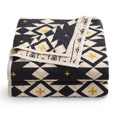 a black and white quilted blanket with gold crosses on the bottom, along with two matching throw pillows