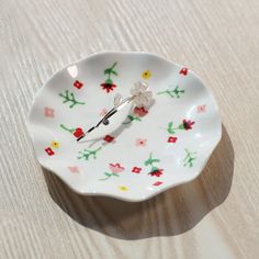 a small white flowered plate with a clock on it