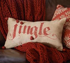 a pillow with the word jingle on it sitting next to some red and white pillows