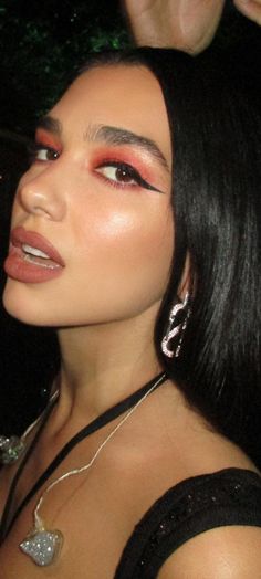 a woman with long black hair and red eyeshadow is posing for the camera