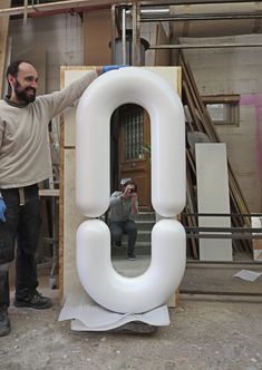 a man standing next to a giant letter shaped like the letter q in front of him