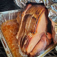 a roasting ham in foil on top of a pan filled with gravy