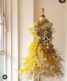 a mannequin is covered with flowers and greenery in front of a window