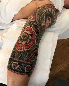 a man laying in bed with a tattoo on his arm