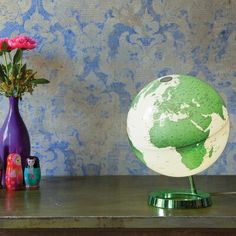 a green and white globe sitting on top of a wooden table next to vases