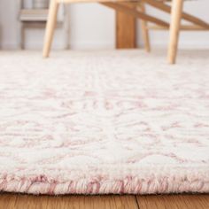 a white rug on the floor in a room with wooden chairs and a table behind it