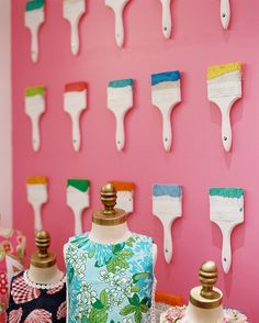 several different types of paintbrushes on display in front of a pink wall with flowers