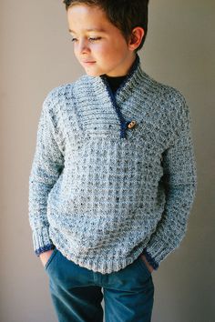 a young boy wearing a blue sweater and jeans