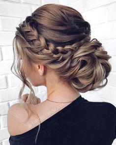 a woman with blonde hair in a low braid updo, looking down at her shoulder