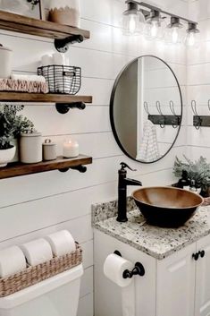 a bathroom with white walls and wooden shelves on the wall, a round mirror above the sink