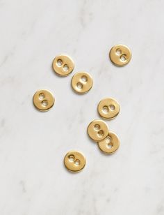 six gold buttons on a white marble surface