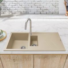 a kitchen sink sitting on top of a counter next to a wooden cabinet and potted plant