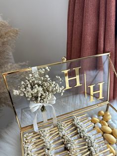 a glass box filled with cookies and flowers on top of a white table next to a red curtain