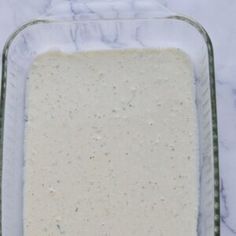 a casserole dish filled with white sauce on top of a marble countertop