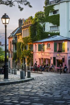 people are sitting at tables in front of some buildings