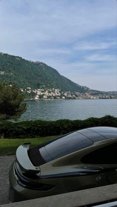 a car parked next to a lake with mountains in the background