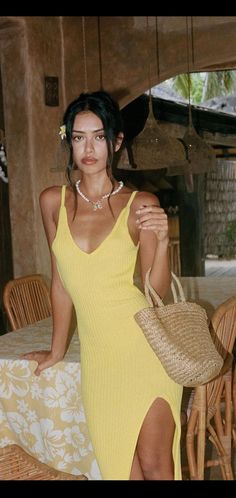 a woman in a yellow dress sitting at a table with a straw hat on her head