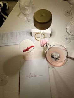 a table topped with glasses and cards on top of a white cloth covered tablecloth