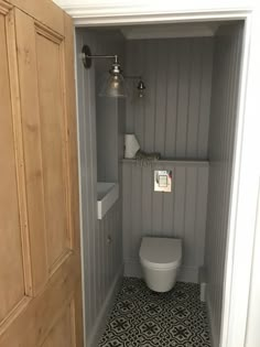 an open door leading to a bathroom with a toilet in the corner and black and white floor tiles