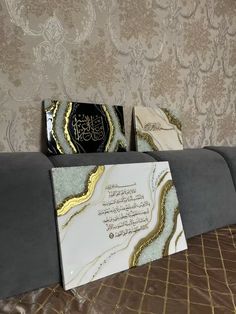 two cards sitting on top of a couch next to a wall with gold and black designs