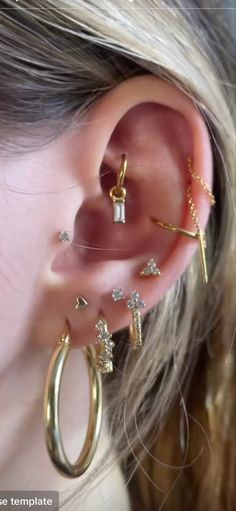 a woman wearing three different types of ear piercings