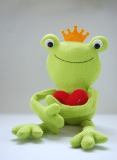 a stuffed frog holding a heart with a crown on its head