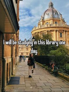 someone walking down the street in front of a building that says i will be studying in this library one day