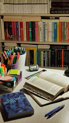 an open book sitting on top of a wooden table next to a pile of books