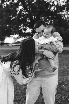 a man and woman holding a baby in their arms