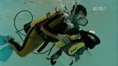 a scuba diver in the water with his gear and mask on, looking up at the camera