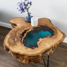 a table made out of a tree trunk with blue water in the center and flowers on top