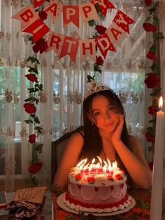 a woman sitting in front of a birthday cake with lit candles on it and the words happy birthday above her